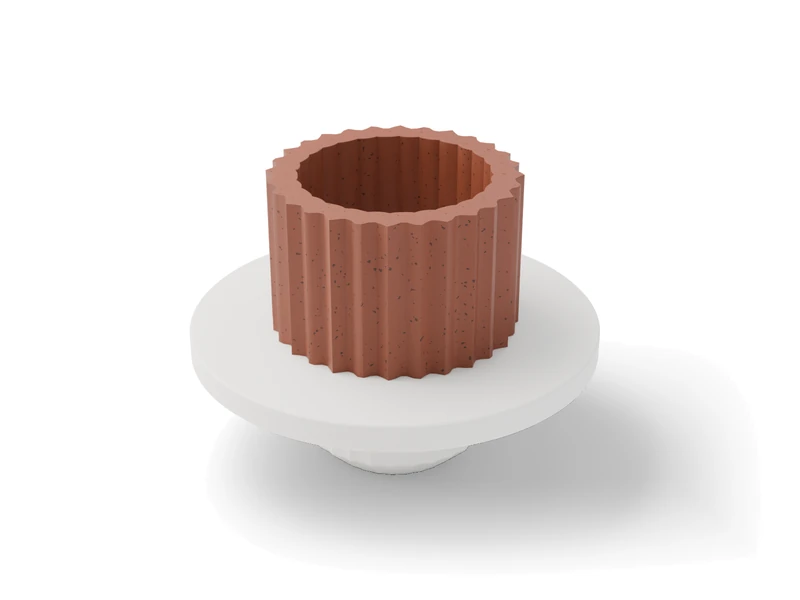 A white printed extruder die with a short fluted clay tube standing in its opening