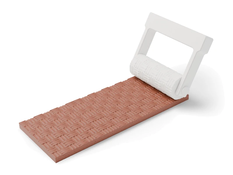 A white printed texture roller on a clay slab carrying its basket-weave pattern